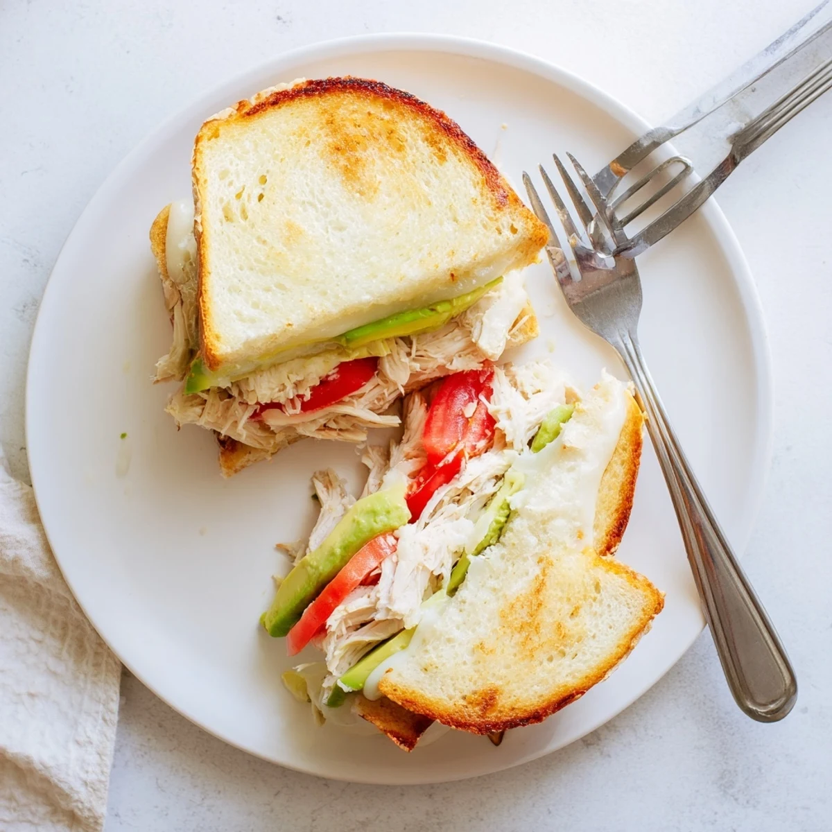 Golden chicken avocado melt sandwich with melted cheese on toasted sourdough bread