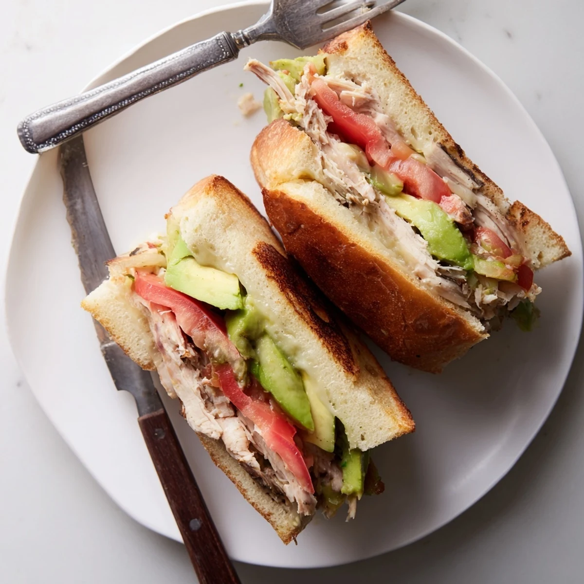 Crispy chicken avocado melt sandwich halved revealing creamy avocado and melted provolone