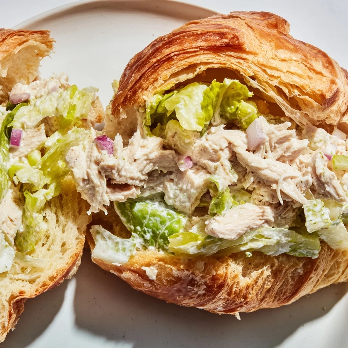 Golden flaky croissant stuffed with creamy Chicken Caesar Salad Croissant Sandwich and crisp romaine lettuce