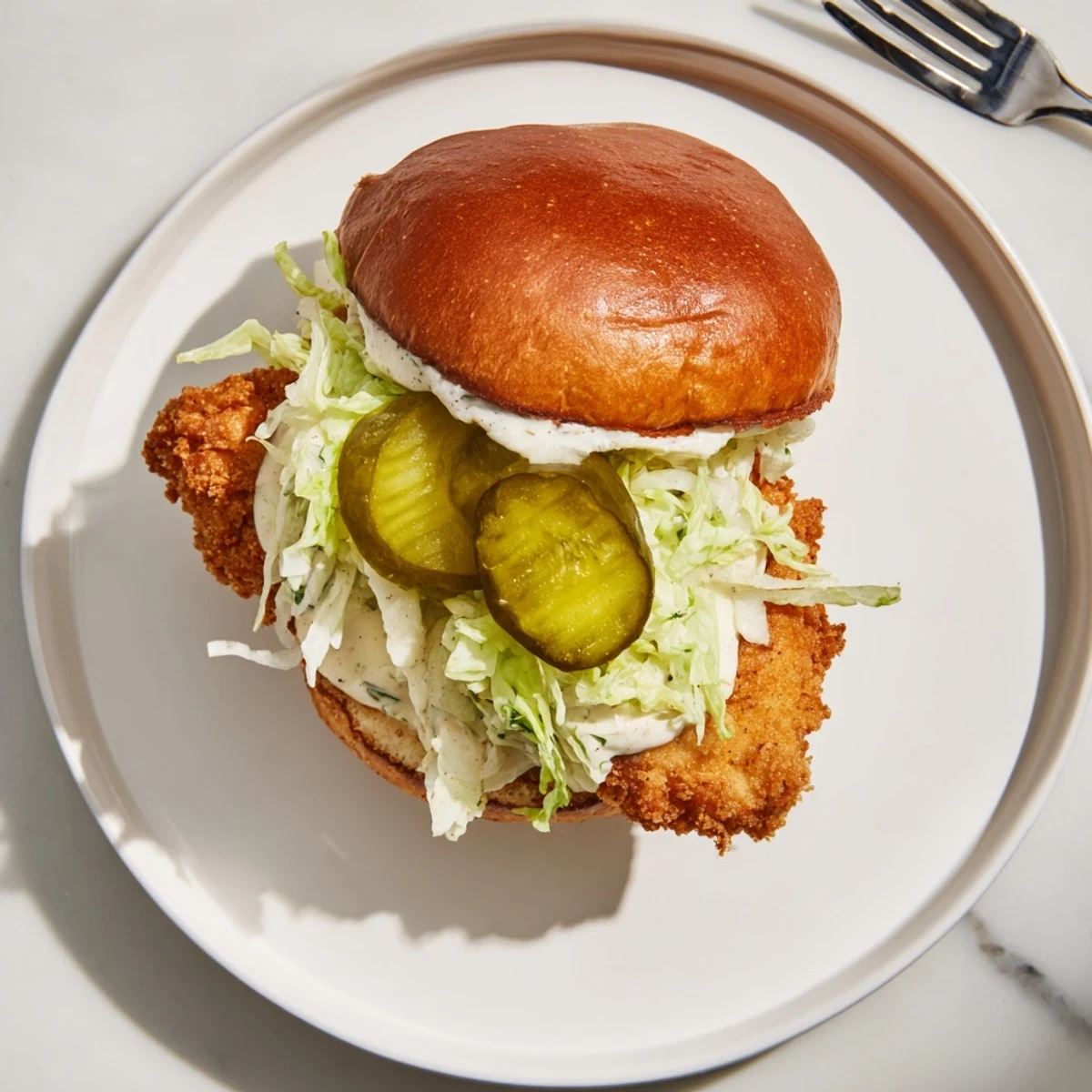 Handheld crispy dill chicken sandwich showing crunchy texture with fresh dill and pickles