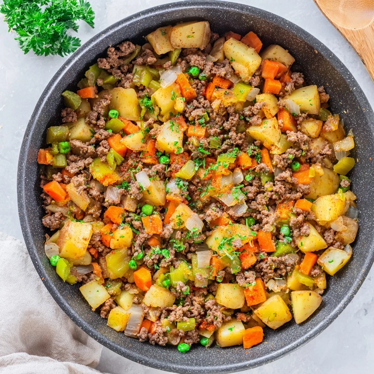 Hearty ground beef and potatoes simmering together in a cast iron skillet with tender carrots and peas
