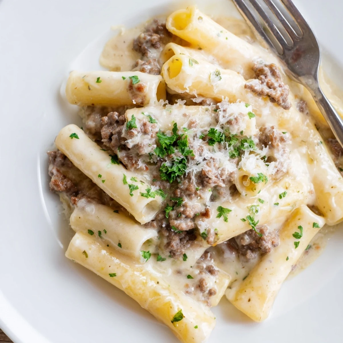 Savory ground beef pasta in a luscious cream sauce garnished with fresh parsley and grated cheese