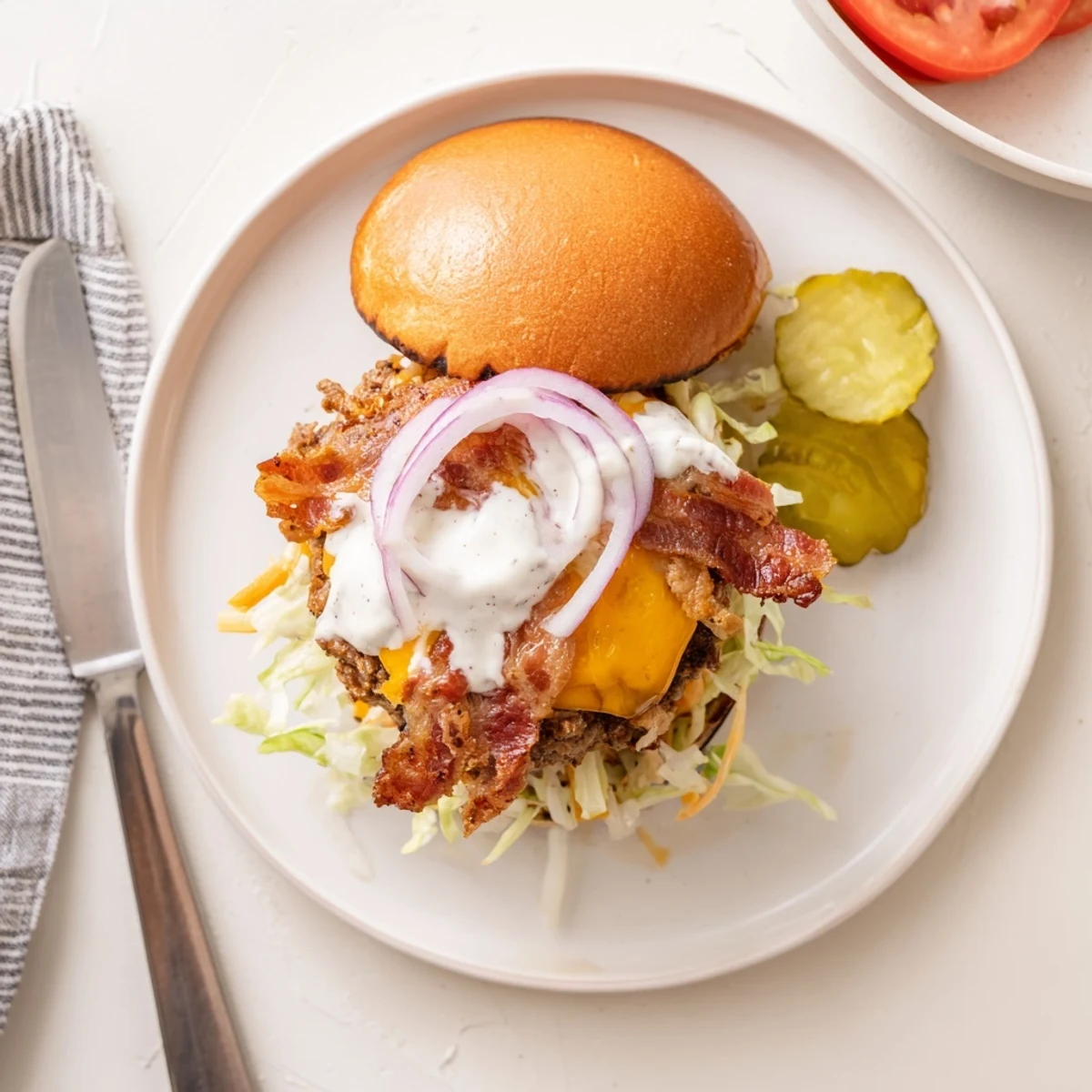 Juicy crack burger stacked with crispy bacon melted cheddar and creamy white ranch sauce on toasted brioche bun