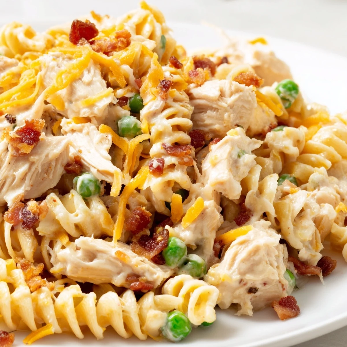 Creamy Crack Chicken Casserole served in a white bowl, featuring shredded chicken, spiral pasta, peas, and a rich bacon cheddar sauce