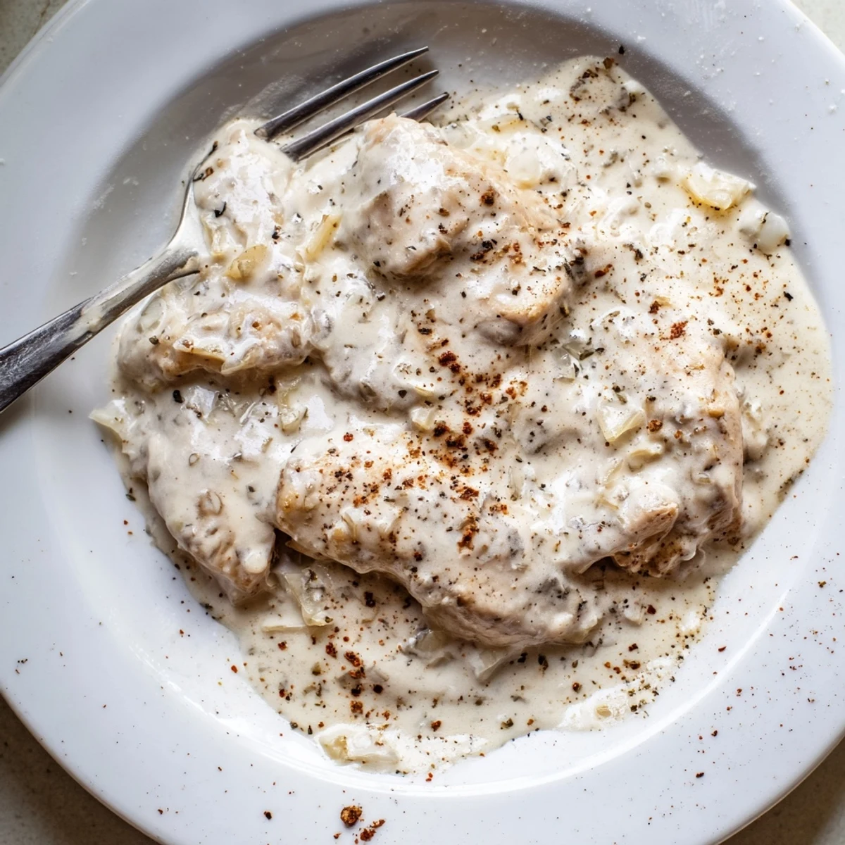 Golden brown chicken thighs swimming in a rich, velvety creamy gravy sauce