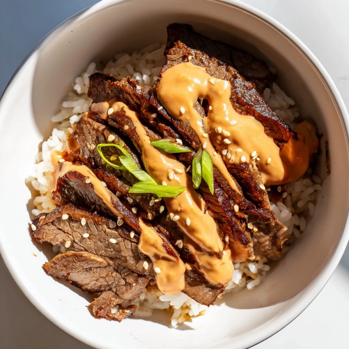 Korean BBQ steak rice bowls drizzled with spicy cream sauce over crisp veggies