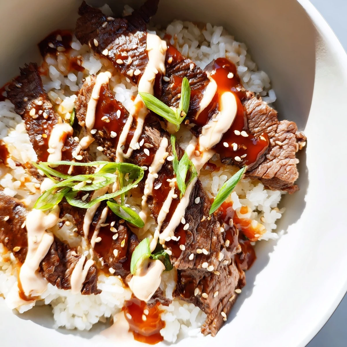 Sizzling Korean BBQ steak rice bowls topped with kimchi and spicy cream sauce