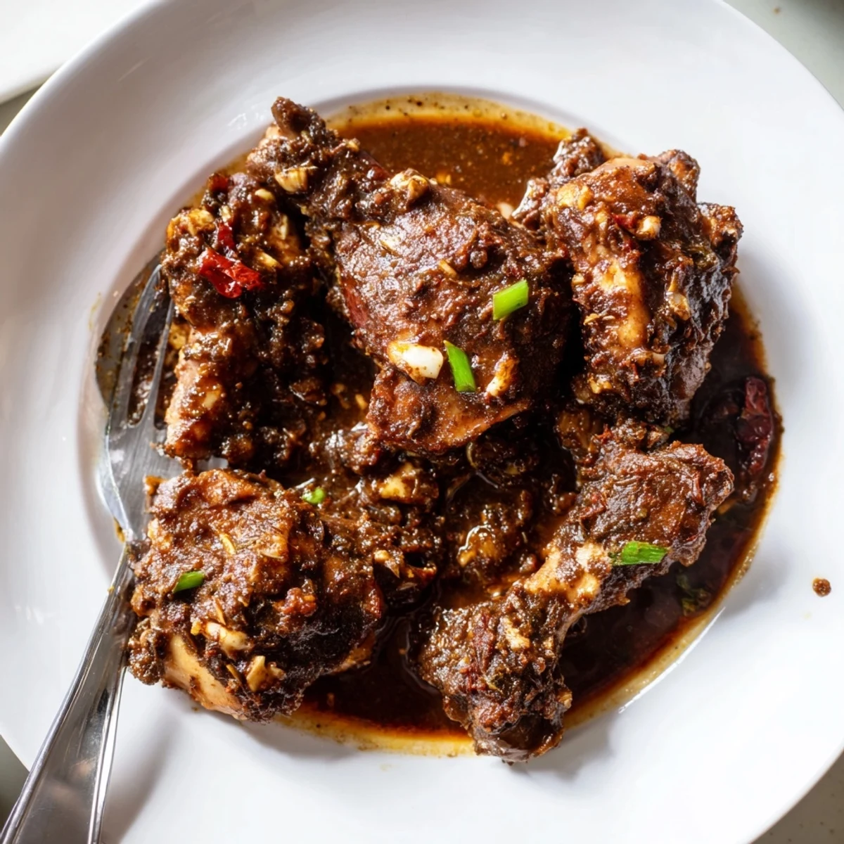 Jamaican brown stew chicken served over steamed white rice with thick sauce