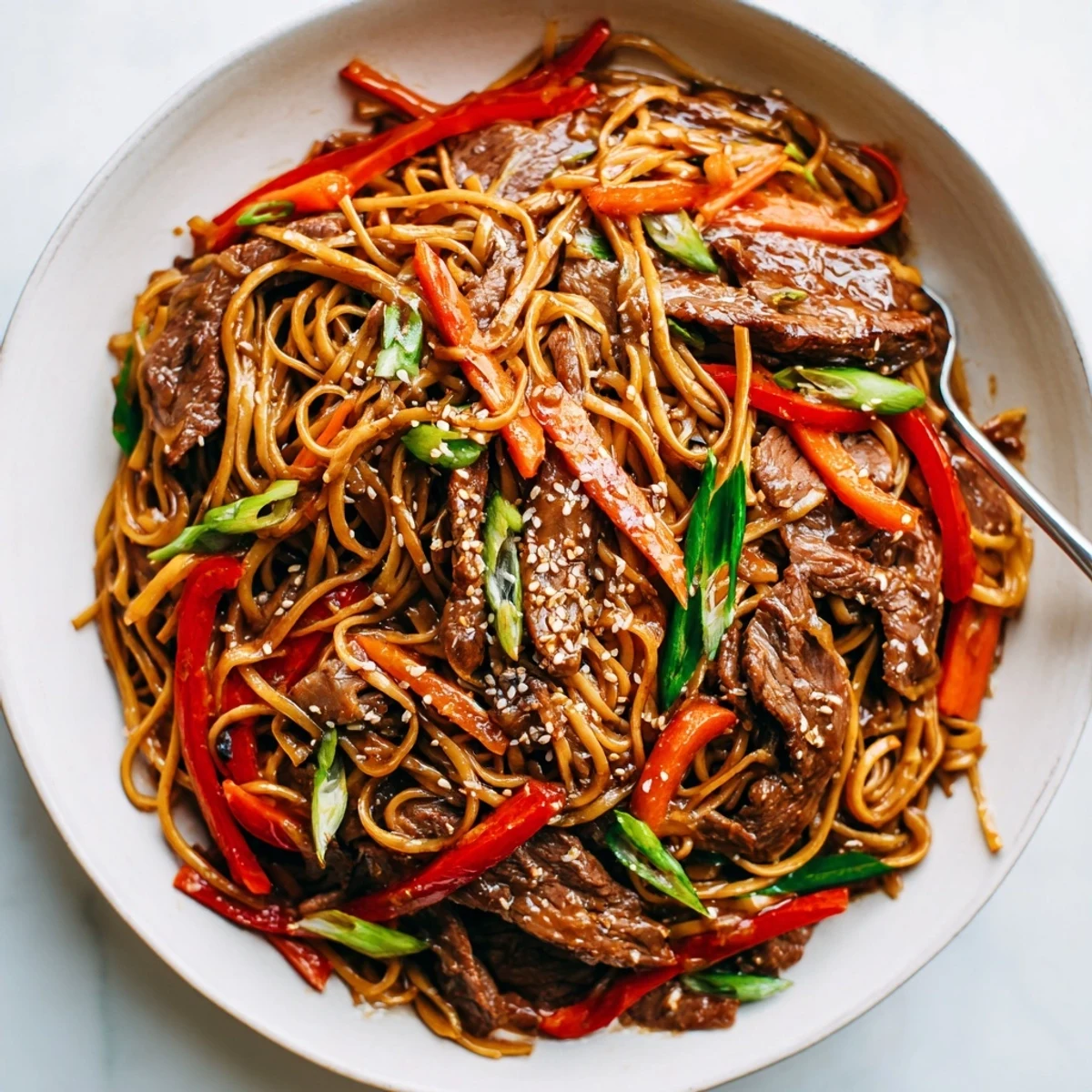 Sticky Beef Noodles glistening with glossy sauce, tossed with crunchy scallions