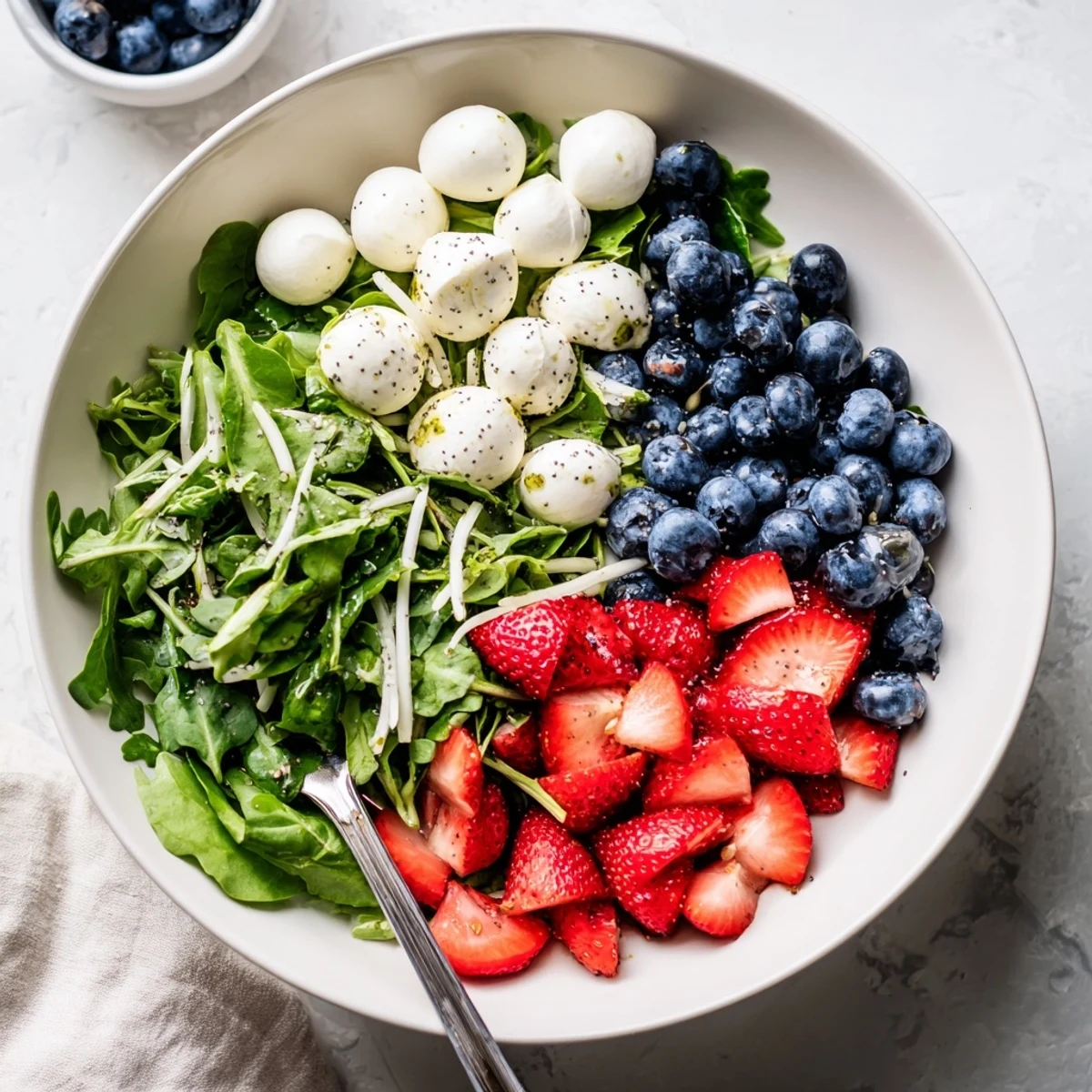Bright 4th Of July Salad served at picnic with berries and creamy mozzarella.