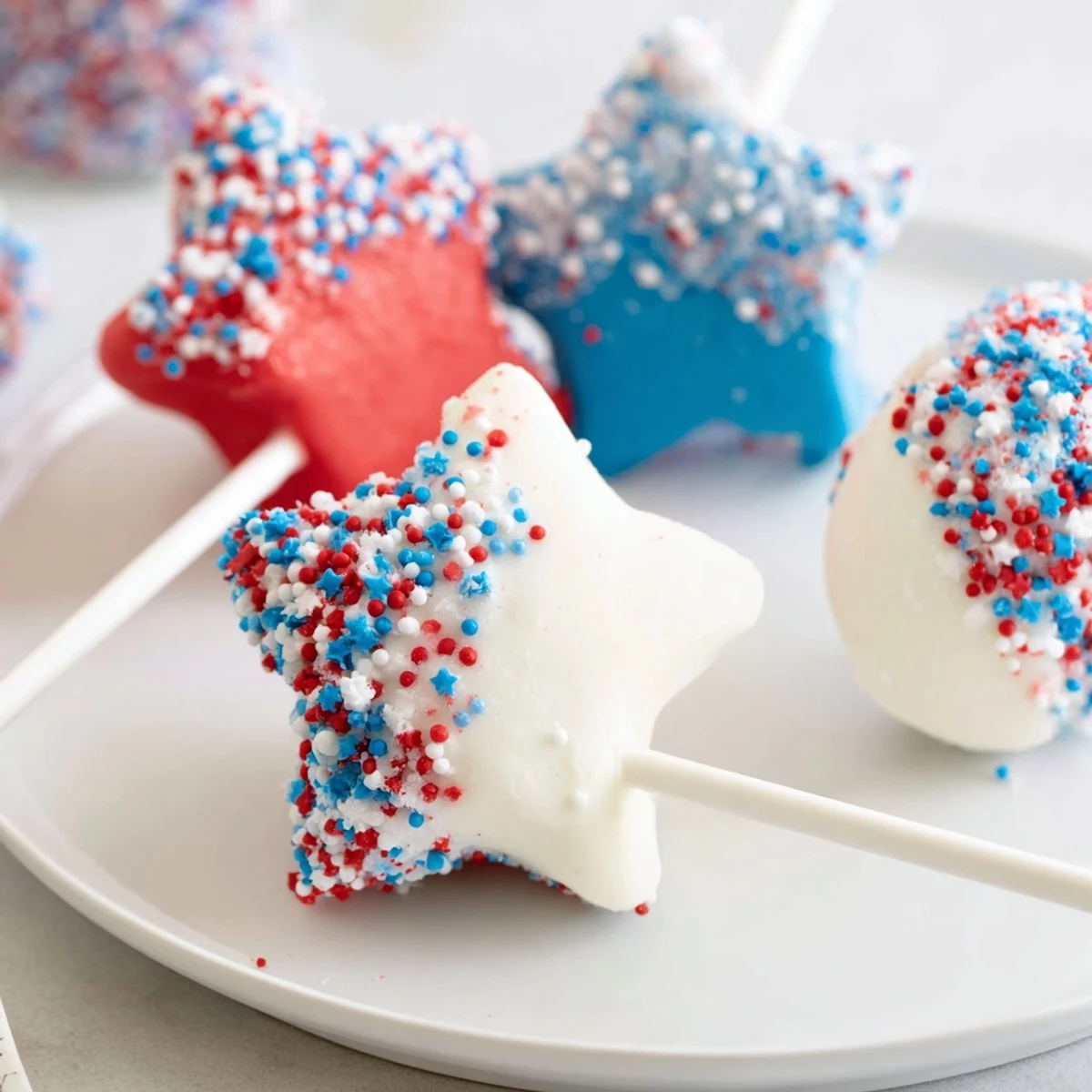 Bright red, white, and blue Fourth Of July Star Cheesecake Pops with sprinkles