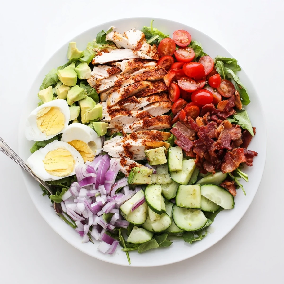 Golden sliced grilled chicken atop vibrant mixed greens with avocado, bacon, and hard-boiled eggs in this Paleo Grilled Chicken Cobb Salad
