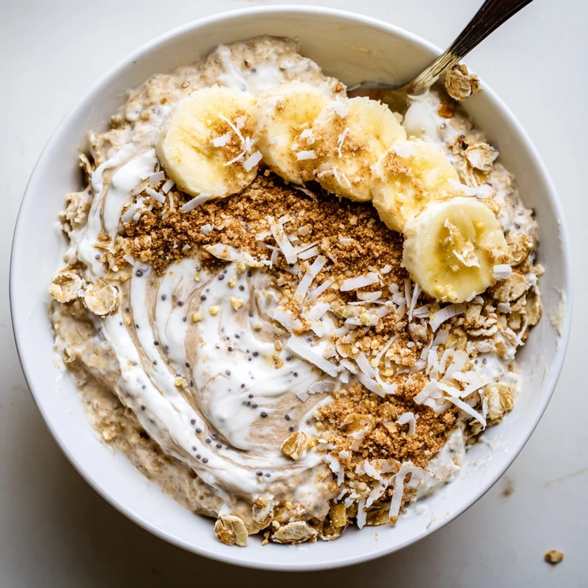 Coconut Cream Pie Overnight Oats topped with toasted coconut and banana slices