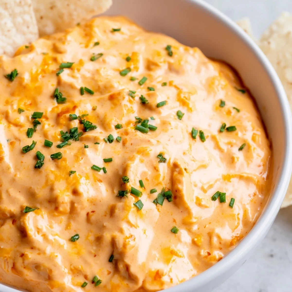 Warm cheese dip in a bowl garnished with fresh chives and paprika