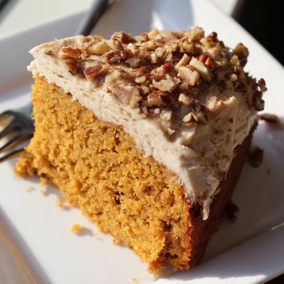 Warm spiced pumpkin pecan cake topped with fluffy cinnamon cream cheese frosting and pecan halves