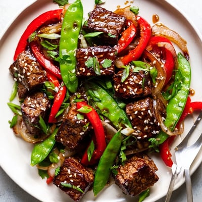 Savory Asian inspired cube steak sizzling in a wok alongside vibrant bell peppers and snap peas